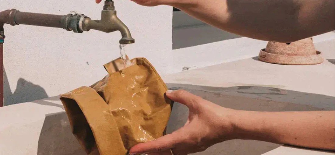 A washable kraft paper bag being rinsed under running water